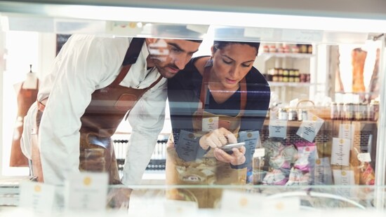 Two people at a supermarket counter registering information on their phone