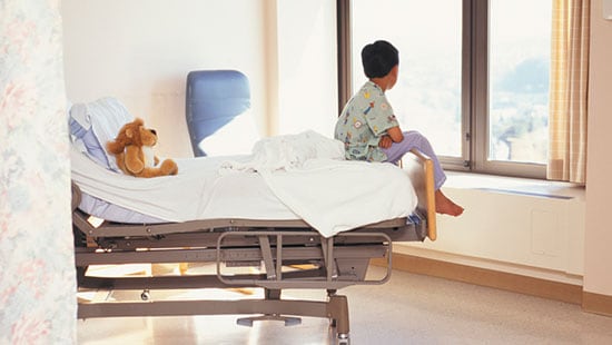 Hospitais e centros cirúrgicos - menino olhando para fora da janela sentado na cama de um hospital
