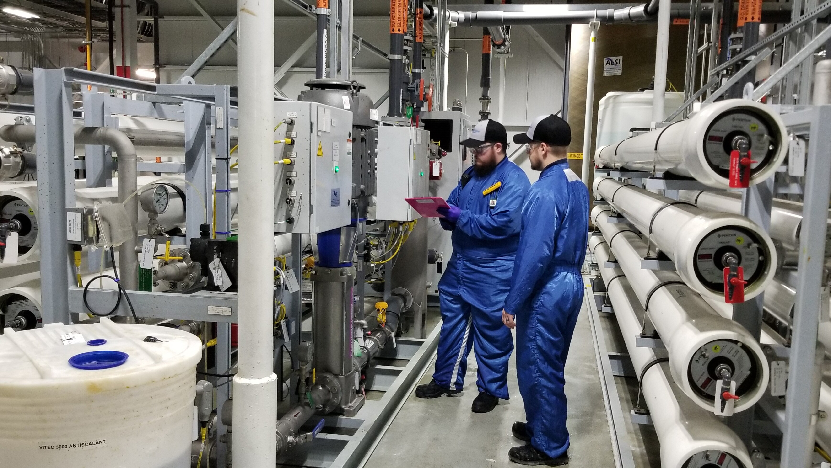 TBM RO filtration inspection Two men inspecting dashboard on RO filtration equipment readings