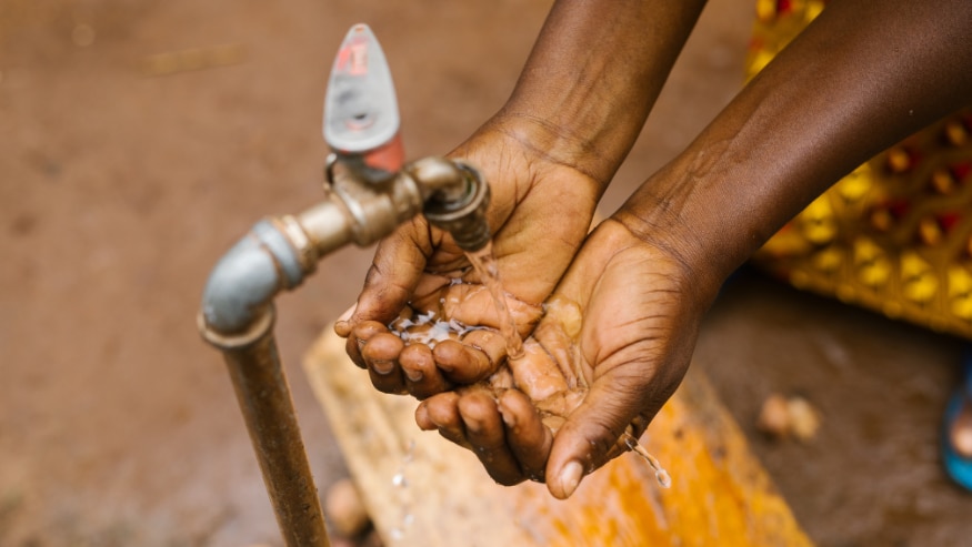 Two hands collecting water from an open tap