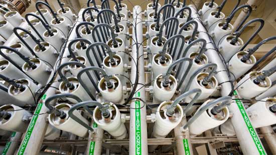 Many industrial canisters with tubes coming out of top end, lined in multiple rows.